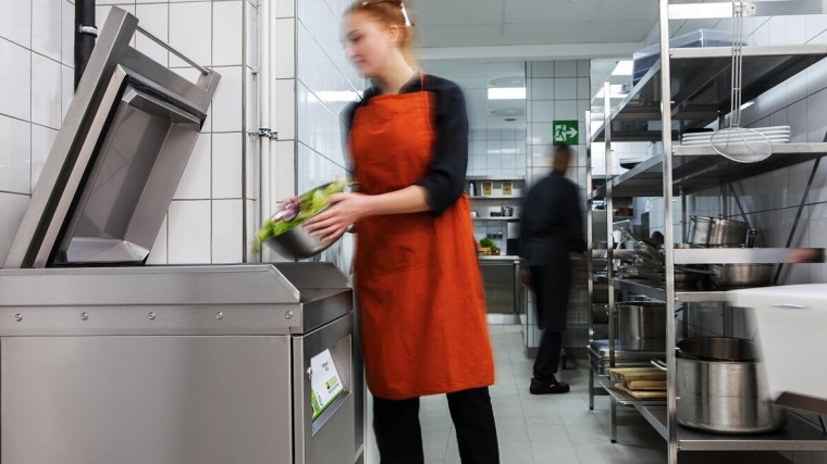 Mitarbeiterin gibt Küchenabfälle in den BioMaster von MEIKO. Foto: Meiko