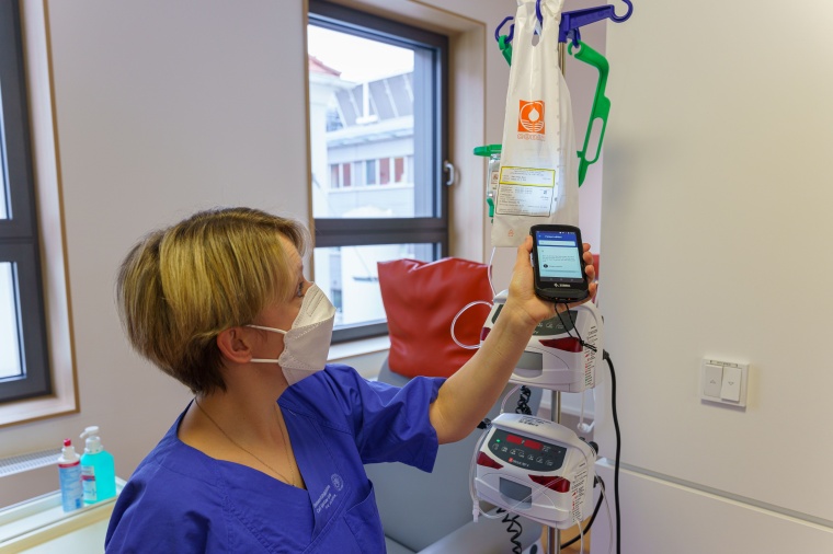 Mithilfe eines mobilen Endgeräts scannt die Pflegekraft den Barcode des zu...